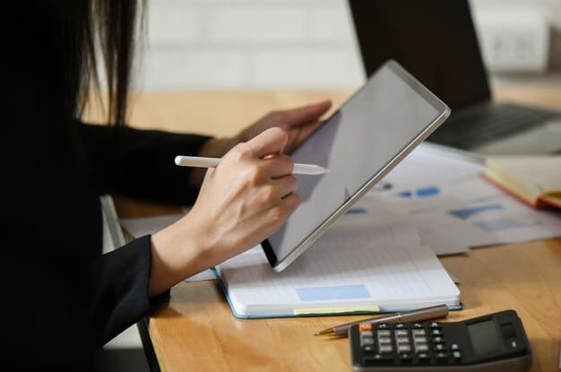 A close-up shot of an employee reviewing their benefits enrollment form on a tablet at their desk, with a calculator and financial planning documents nearby.